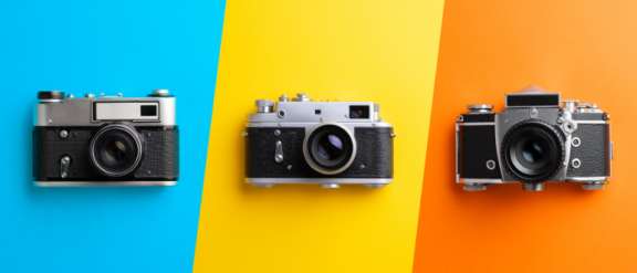 Blue, yellow and orange striped background with three individual black cameras