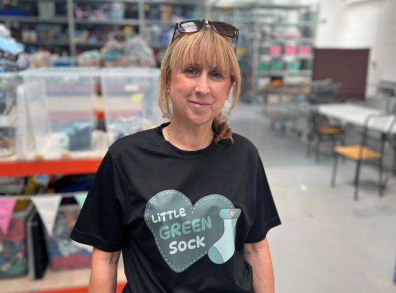 A picture of a woman wearing a black t-shirt containing a logo for the Little Sock charity