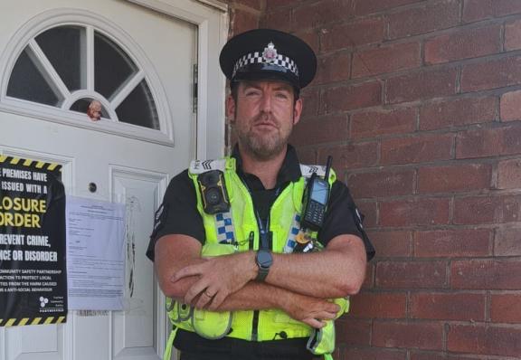 Police officer outside closed house