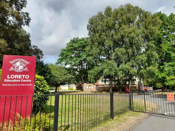 a school building hidden by trees. A red sign on the left says: Loreto Education Centre.