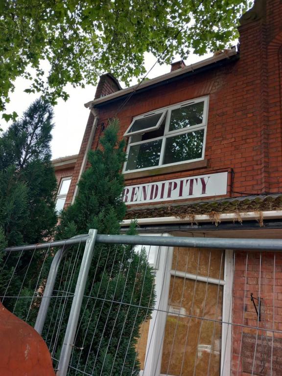 A dilapidated building wthat has been boarded up, surrounded by metal fencing
