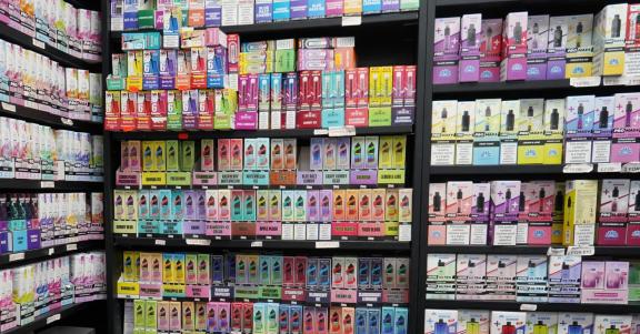 Shelves in a vape shop filled with a wide variety of colourful vaping products and e-liquid packaging.