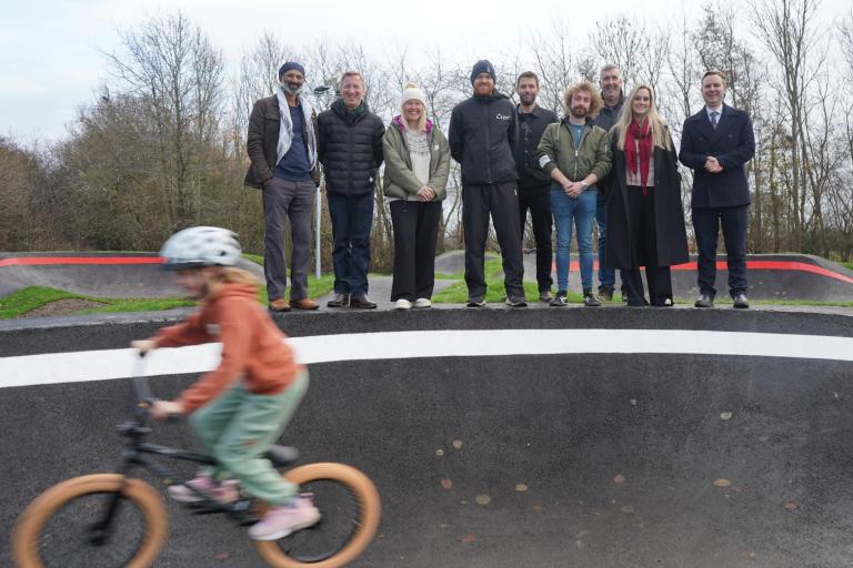 Child on BMX bike riding past a group of Council representatives at BMX track