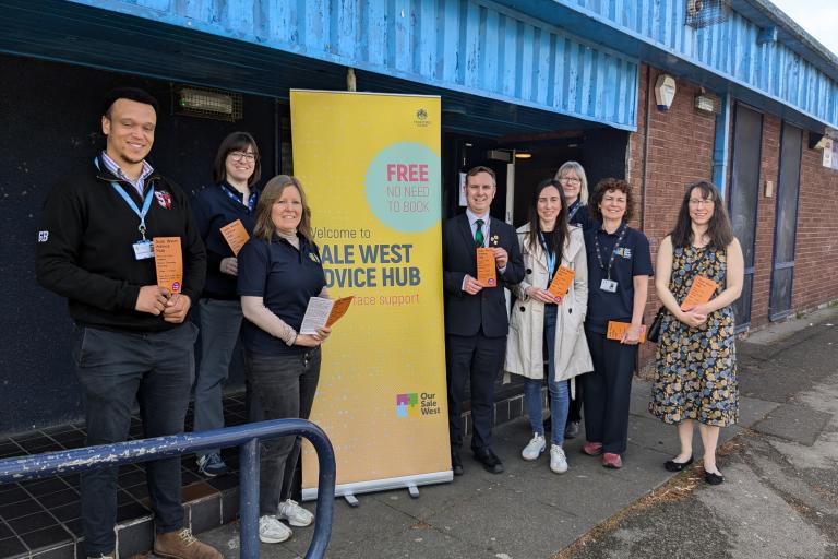Photo of eight representatives from Trafford Council and the community stood outside Sale West Community Hub