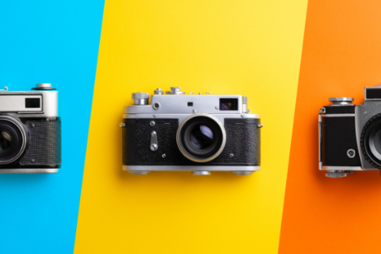 Blue, yellow and orange striped background with three individual black cameras
