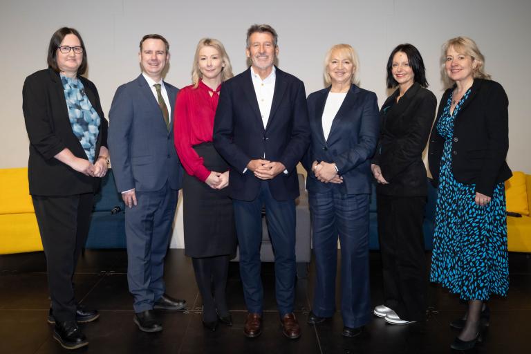 Photo of Old Trafford Regeneration Mayoral Development Corporation speakers stood in a row: Cllr Liz Patel, Cllr Tom Ross, Manchester United’s Chief Operating Officer Collette Roche, Chair Lord Sebastian Coe, Group Chief Executive for GMCA, GMFRS and TFGM Caroline Simpson, non-executive director board member Sukhvinder Kaur-Stubbs and Project Director, Karen Hirst.
