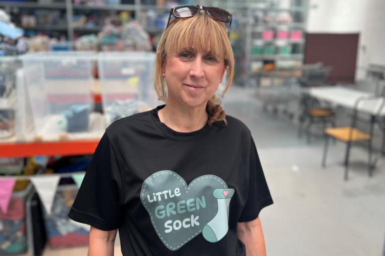 A picture of a woman wearing a black t-shirt containing a logo for the Little Sock charity