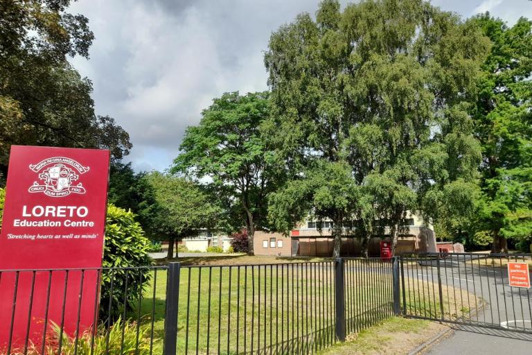 a school building hidden by trees. A red sign on the left says: Loreto Education Centre.