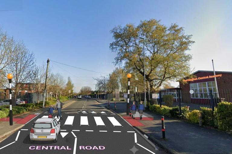 Visualisation of a proposed zebra crossing outside Partington Central Academy. The image shows a road with a new zebra crossing, Belisha beacons, tactile paving and updated road markings.
