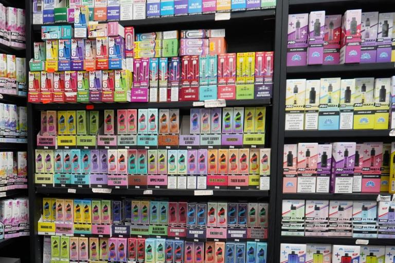 Shelves in a vape shop filled with a wide variety of colourful vaping products and e-liquid packaging.